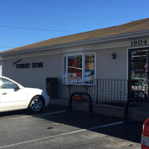 Country store exterior with parked cars and open sign.