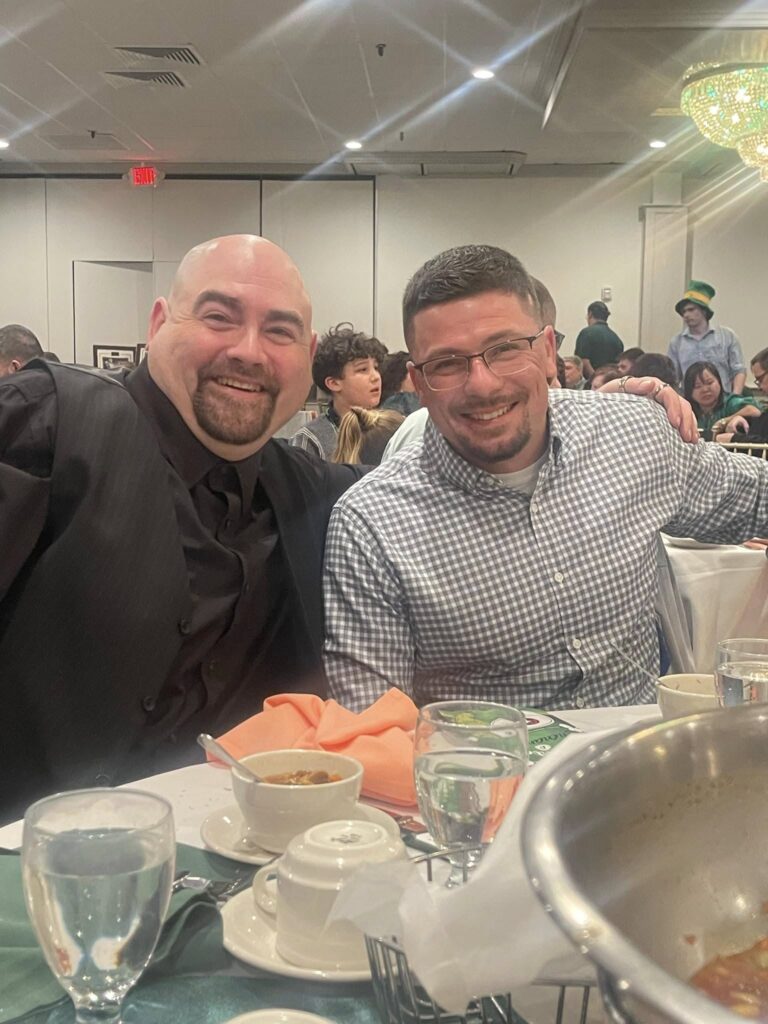 Two smiling men sitting at a festive banquet table
