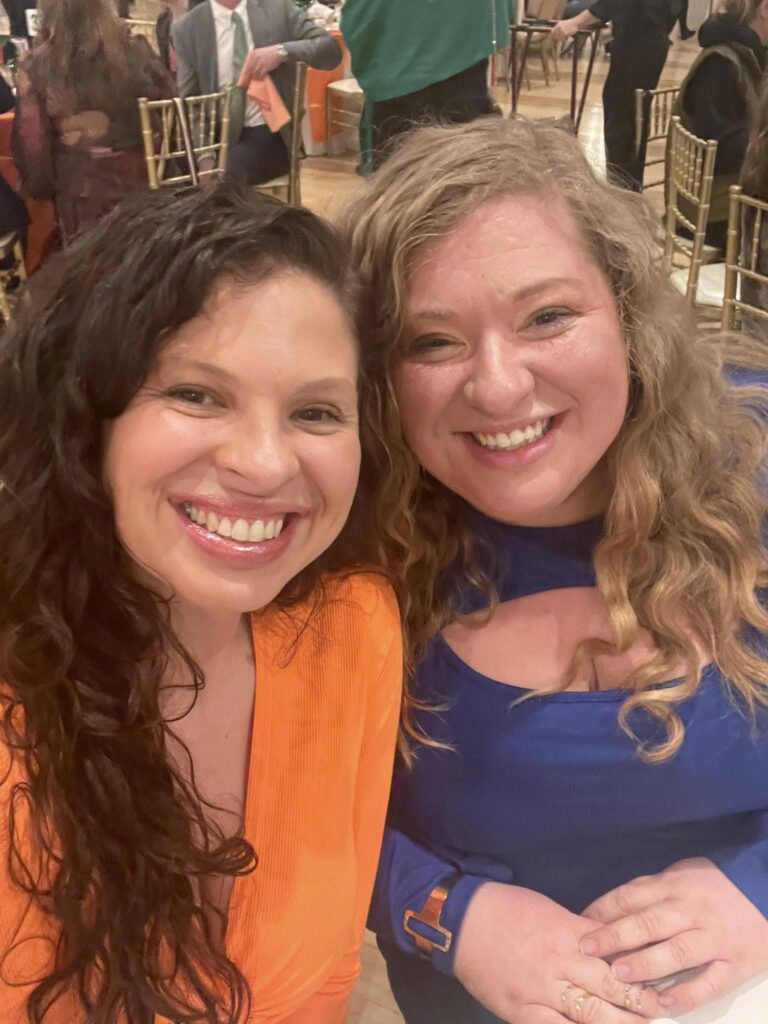 Two women smiling at a social event